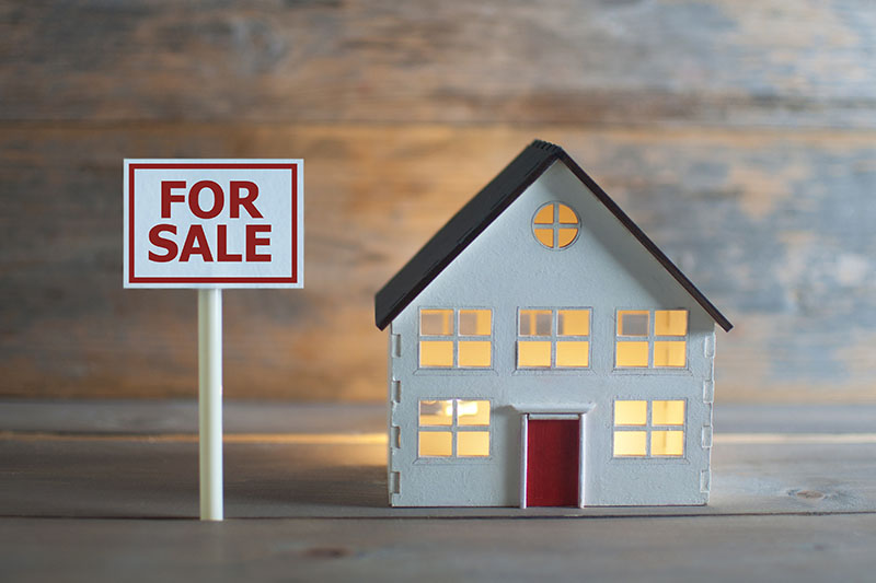 Comment réduire les droits de succession sur un bien immobilier 1 maison avec un panneau a vendre