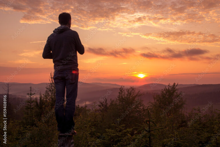 une personne regardant un paysage au coucher de soleil